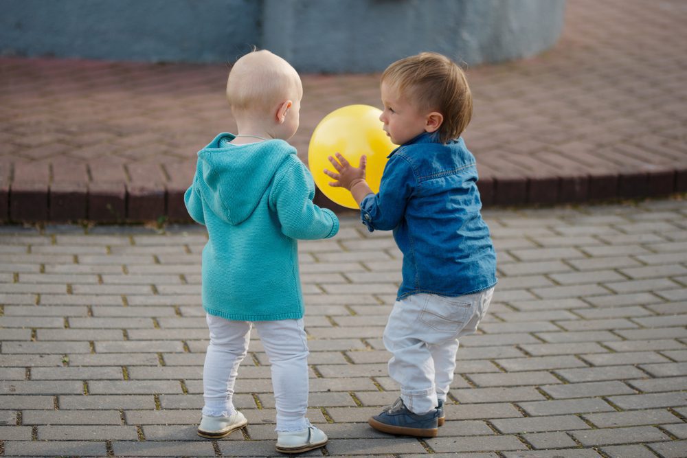 Two young children play with a balloon.