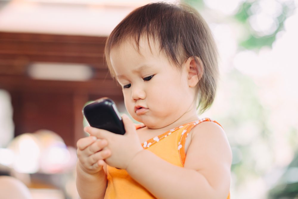 A baby looks at a cell phone.