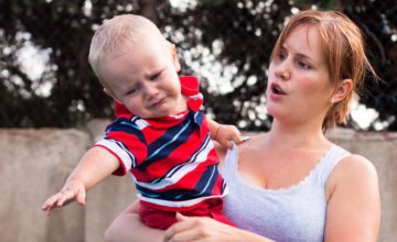 mom holding fussy young boy