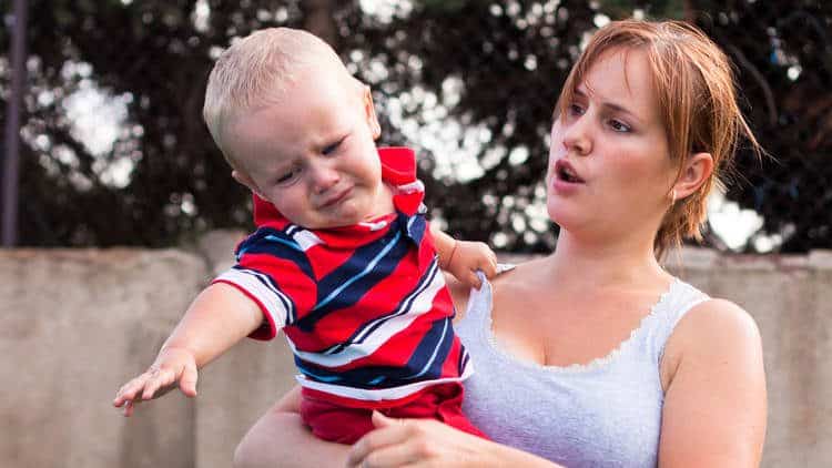 mom holding fussy young boy