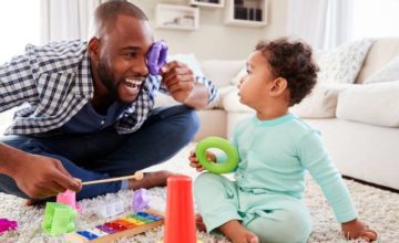 Father playing on the floor with toddler and toys