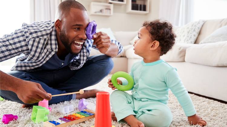 Father playing on the floor with toddler and toys