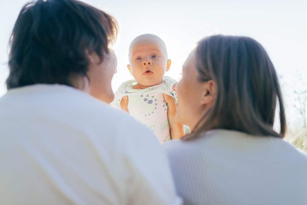 Mother and Father look up toward baby being held up in the air