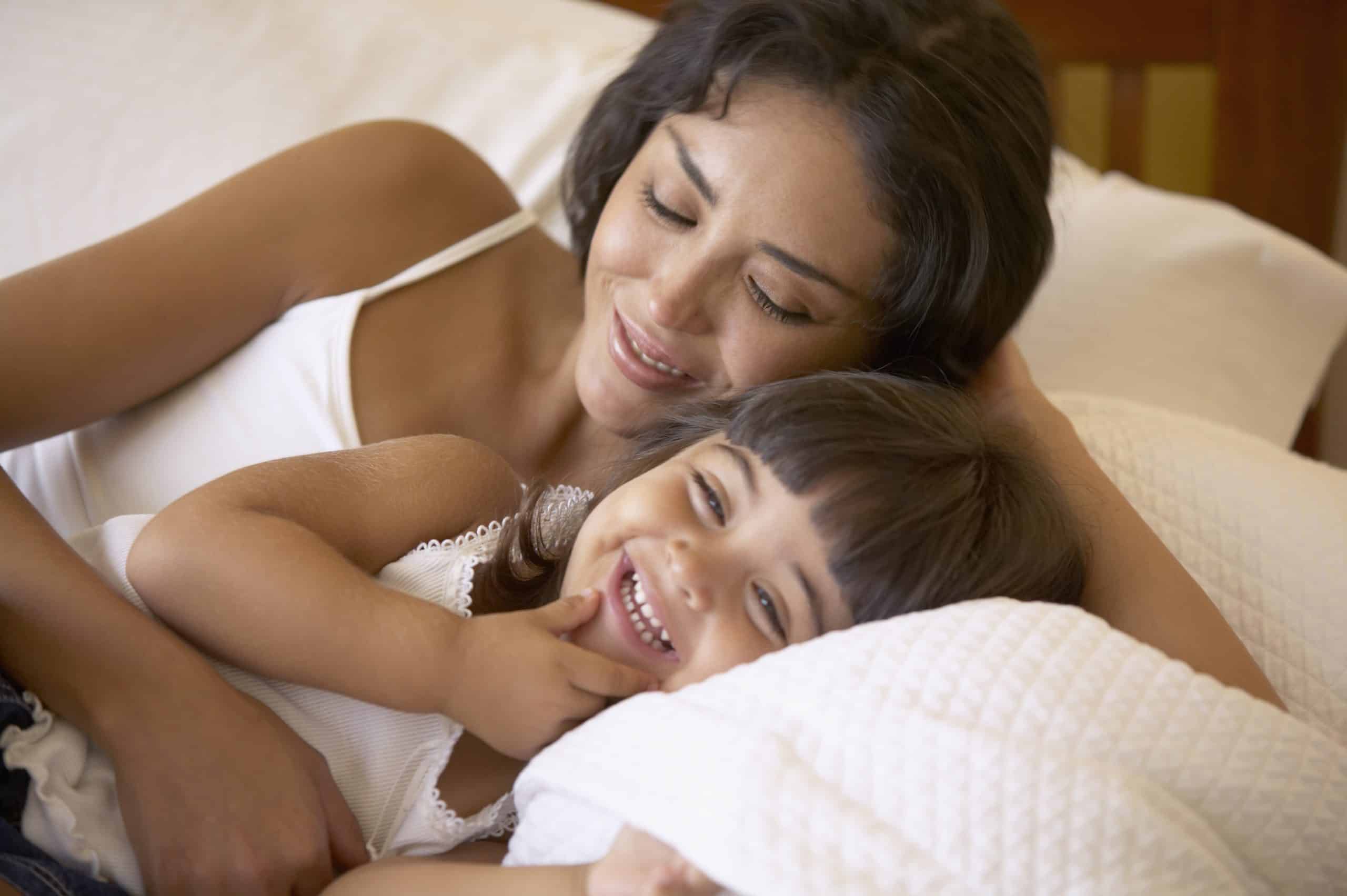 A toddler sleeps in bed with her mother.