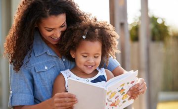 child sitting in mother's lap reading a book