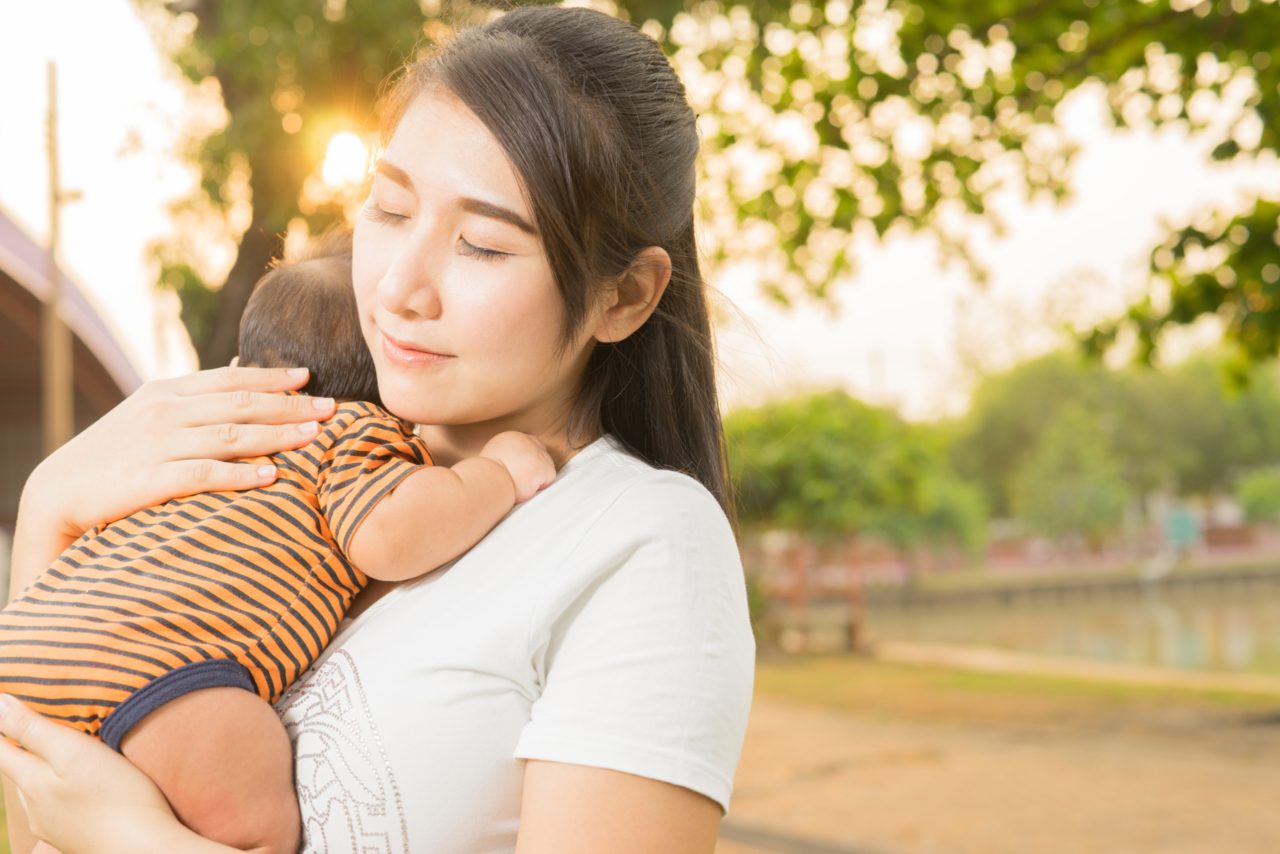 mother hugging baby outside eyes closed