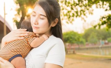 mother hugging baby outside eyes closed