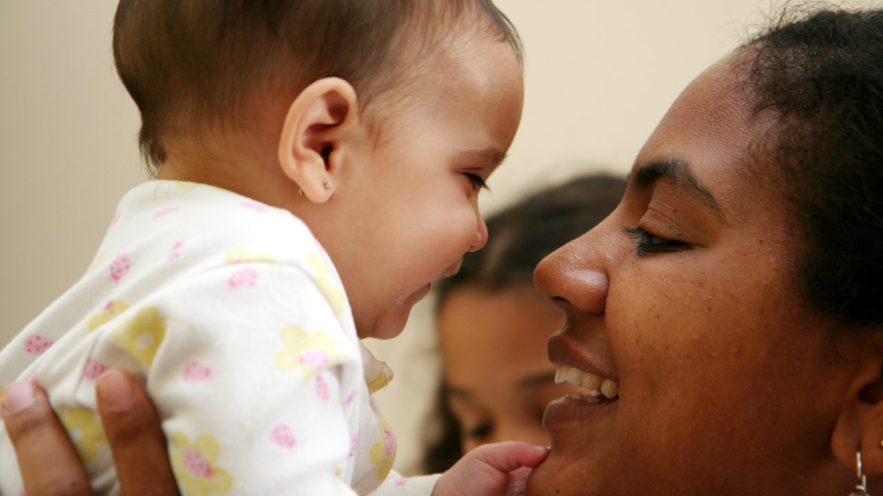 woman holding baby close to face and smiling