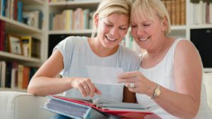 mother and adult daughter looking at photo album