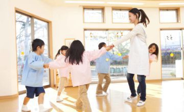 Woman and five children holding hands walking aroundin a circle