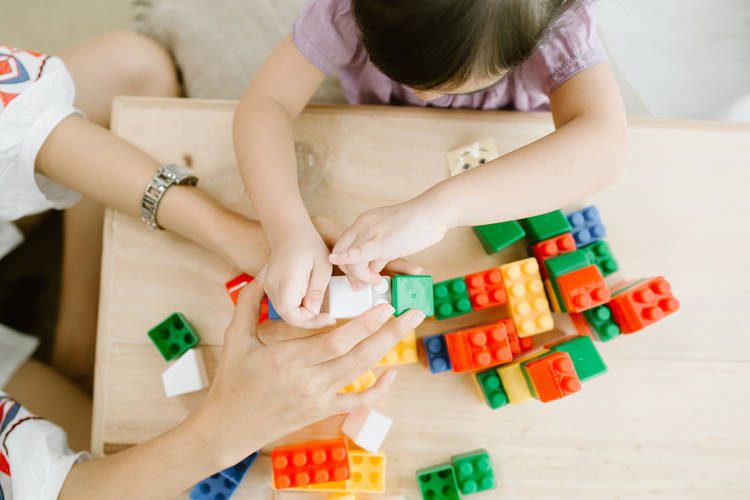 toddler and parent playing with blocks on activity table