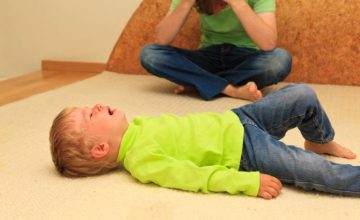 Child on the floor crying and adult holding head in arms