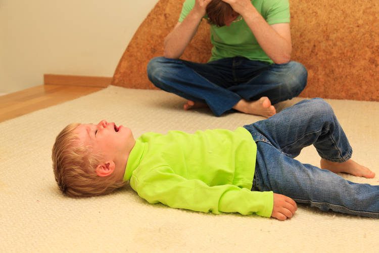 Child on the floor crying and adult holding head in arms