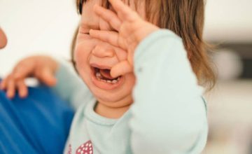 Crying toddler with hand over face