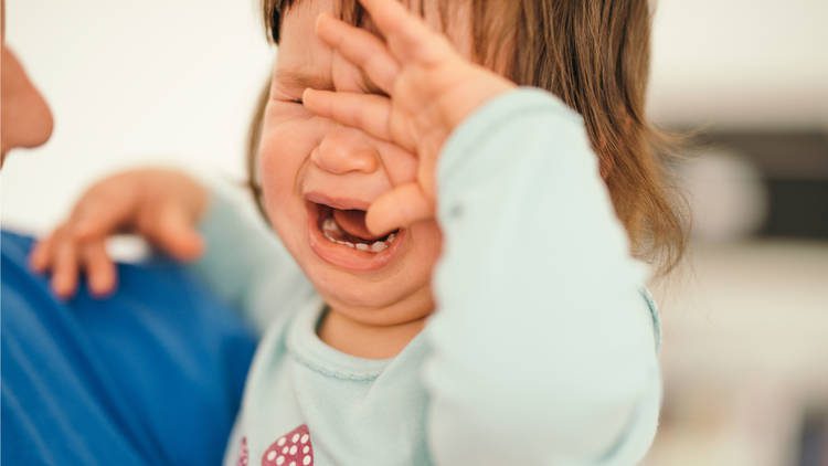 Crying toddler with hand over face