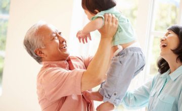 Man carrying infant with woman smiling