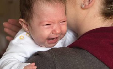 Crying infant help in woman's arms