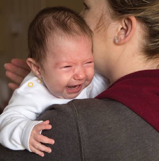 Crying infant help in woman's arms