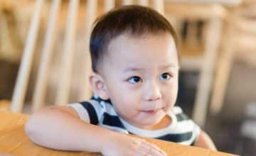 Child sitting at table looking up