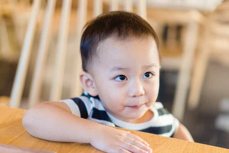 Child sitting at table looking up