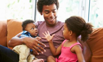 Man smiling with toddler girl and infant