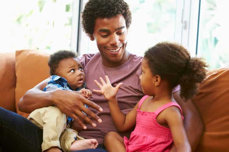 Man smiling with toddler girl and infant