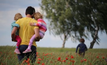 Dad carries children in flower field