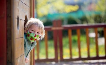 toddler with mask on playground