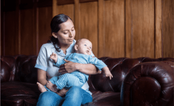 woman holding baby on brown couch