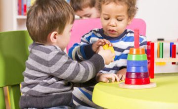 two toddlers playing with stacking toys at table