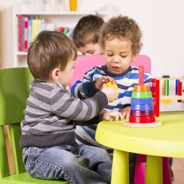 two toddlers playing with stacking toys at table