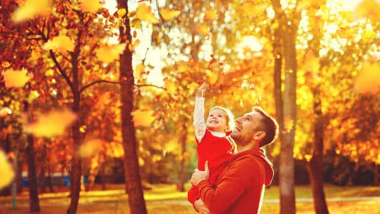 toddler playing in autumn leaves