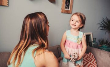 A little girls holds a stuffed toy and looks at mom.