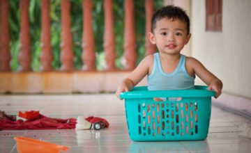 Toddler playing in laundry basket