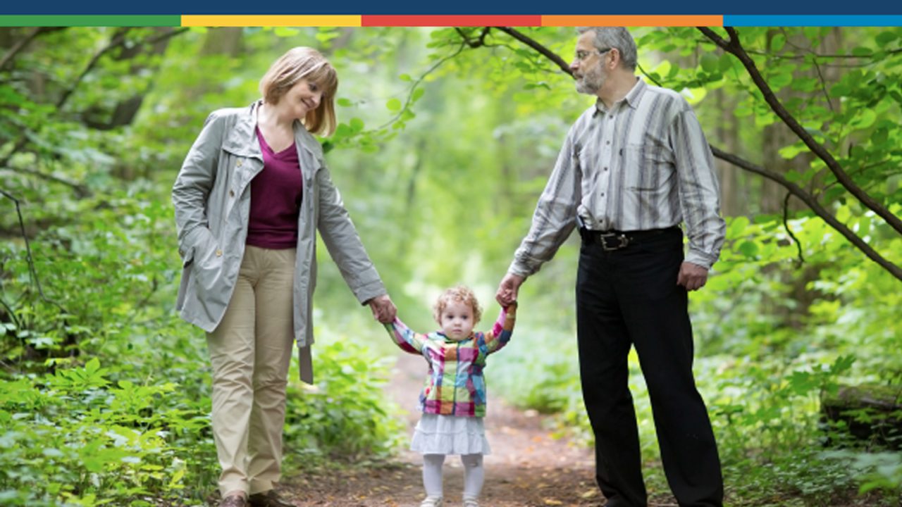 grandparents holding toddler hands in forest