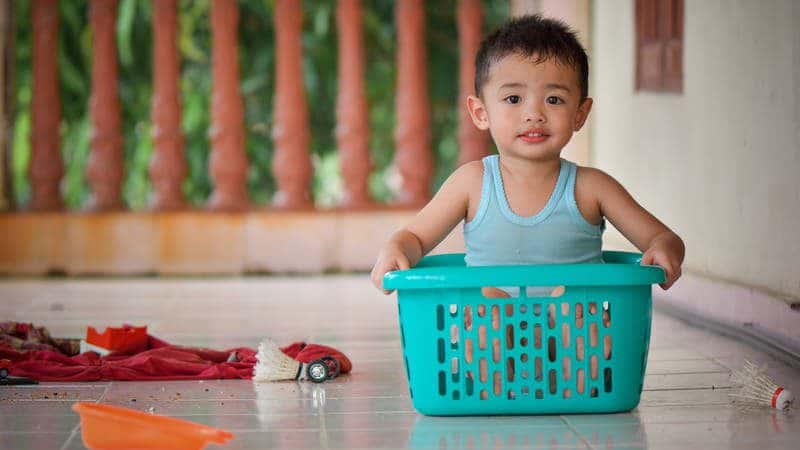 Toddler playing in laundry basket