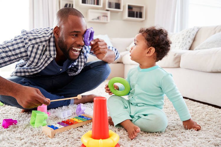 Parent playing with toys with their toddler laughing