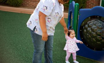 woman and small child play at playground