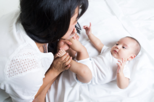 An adult plays with a baby's feet.