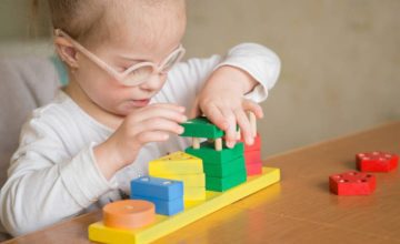 Toddler with glasses playing with blocks
