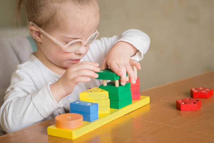 Toddler with glasses playing with blocks