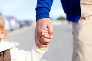 A child holds hands with an adult.