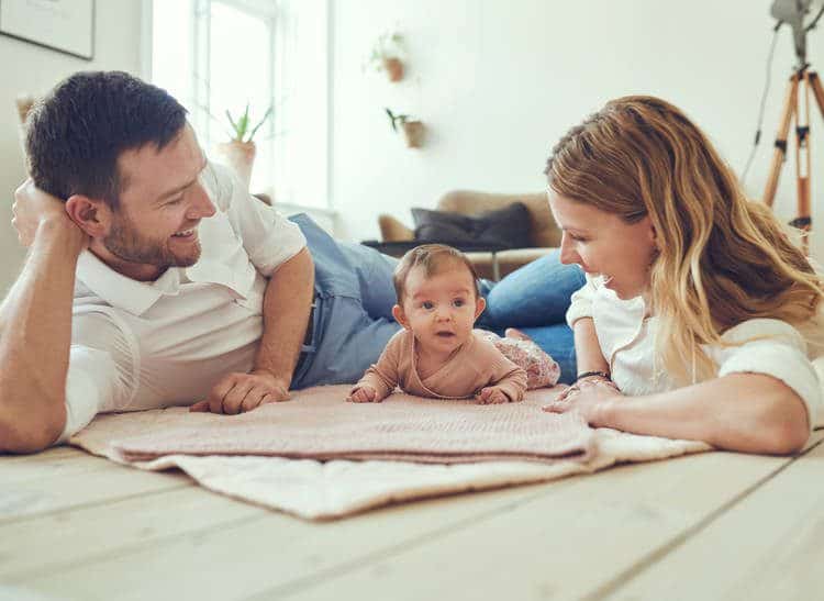 Parents lying on the floor playing with baby