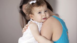 A mother hugs an upset toddler.