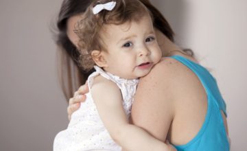 A mother hugs an upset toddler.