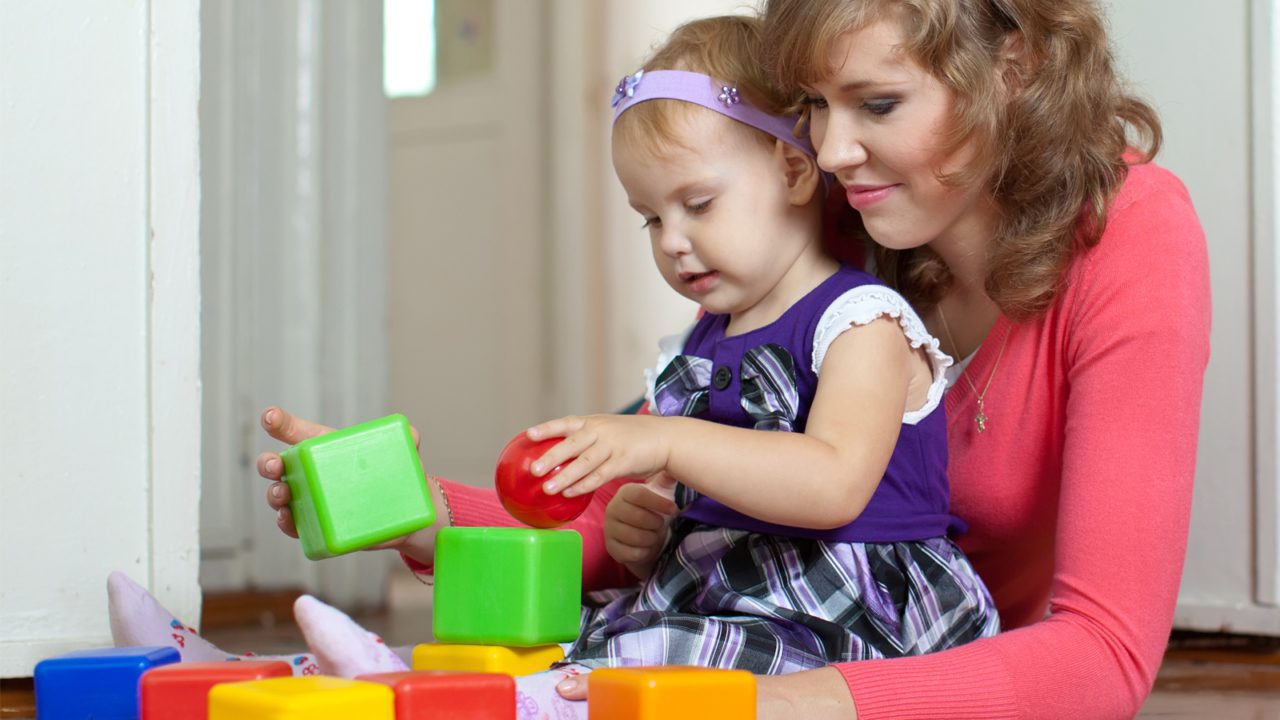 woman holds child playing with blocks