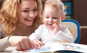 Mother reading a book to a smiling baby