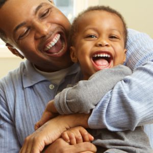 A father holds and laughs with a young child.