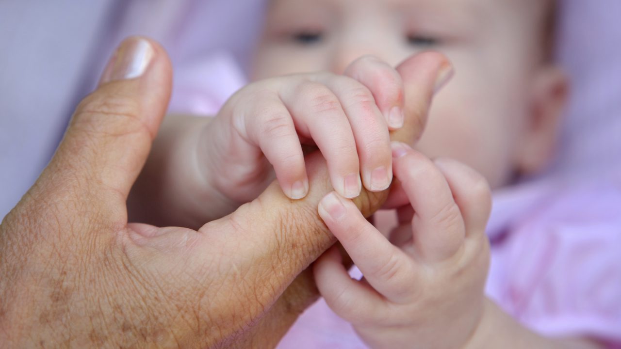 baby grabs adult finger