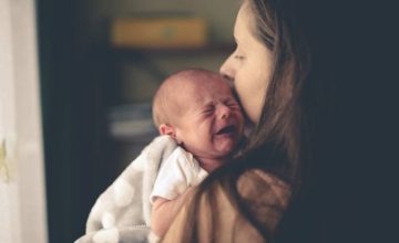 A mom holds a crying baby trying to soothe.